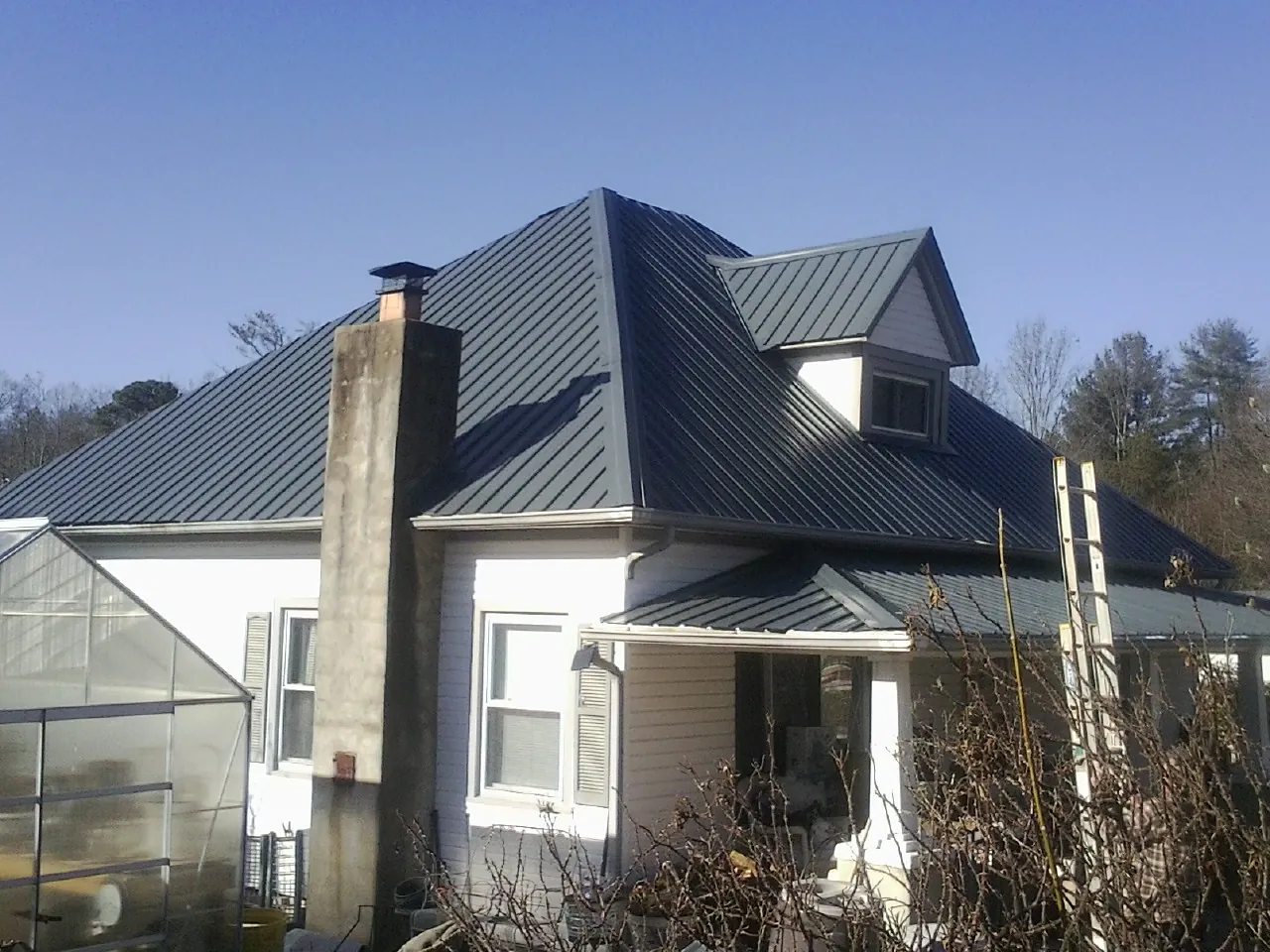 Dark blue standing seam metal roof on a white farmhouse with dormer — Slate & Tile Roof Repair by Roofing Brothers in Bettsville