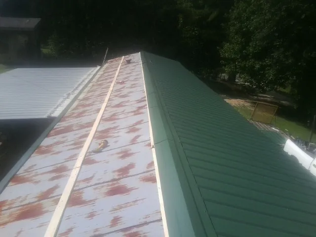 Old rusted panels beside newly installed green metal roofing — Wind Damage Roof Repair by Roofing Brothers in Bettsville