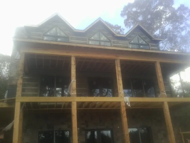 Dormers and porch framing on a large log home under construction — Roof Coating work by our crew in Bettsville