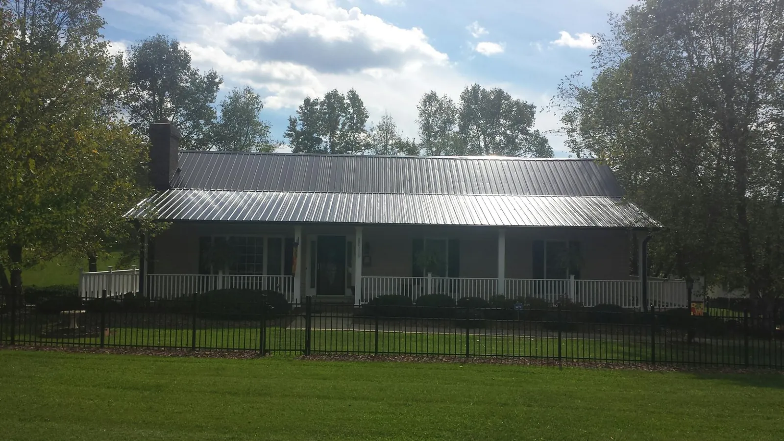 Gray metal roof on a brick ranch with a full width front porch — Gutter Guard Installation work by our crew in Bettsville