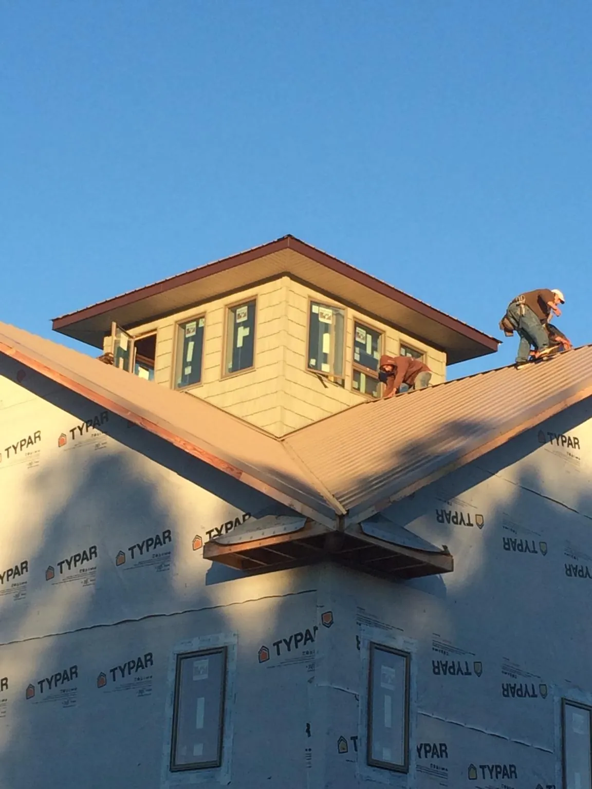 Roofers working around a rooftop cupola on a new metal roof at sunset — Roof Waterproofing in Bettsville by Roofing Brothers